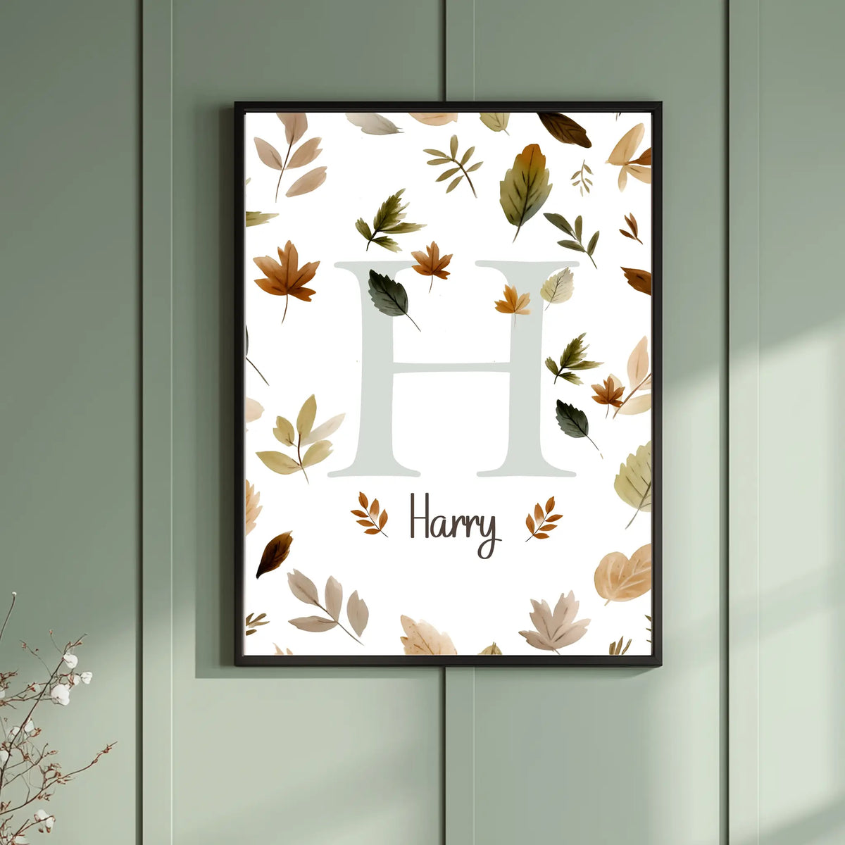 Framed artwork with leaf pattern and 'H' and 'Harry' text on a light green wall.