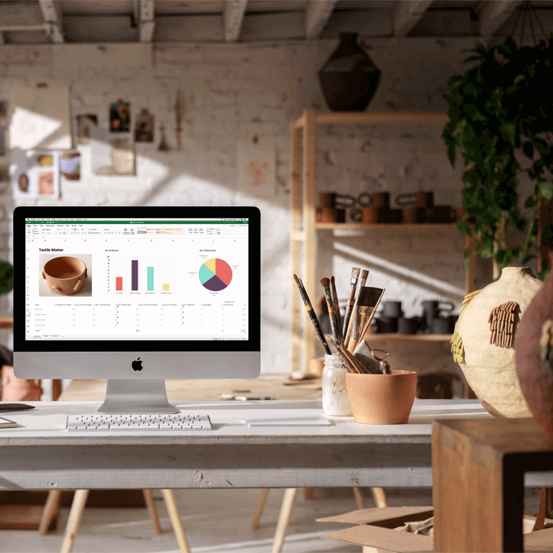 Office room with white desk and computer, a bowl of paint brushes
