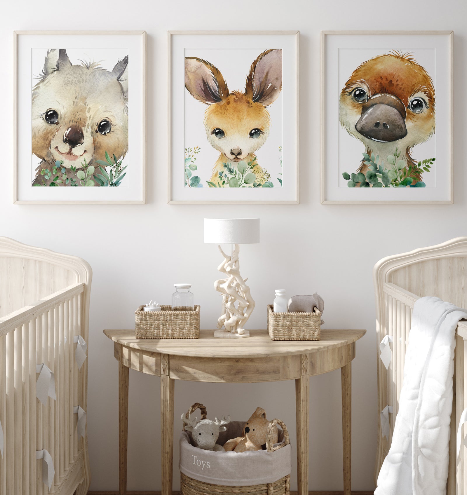 A set of three framed wall prints featuring Australian animals, including a koala, a kangaroo, and a wallaby, displayed above a wooden table in a nursery room.