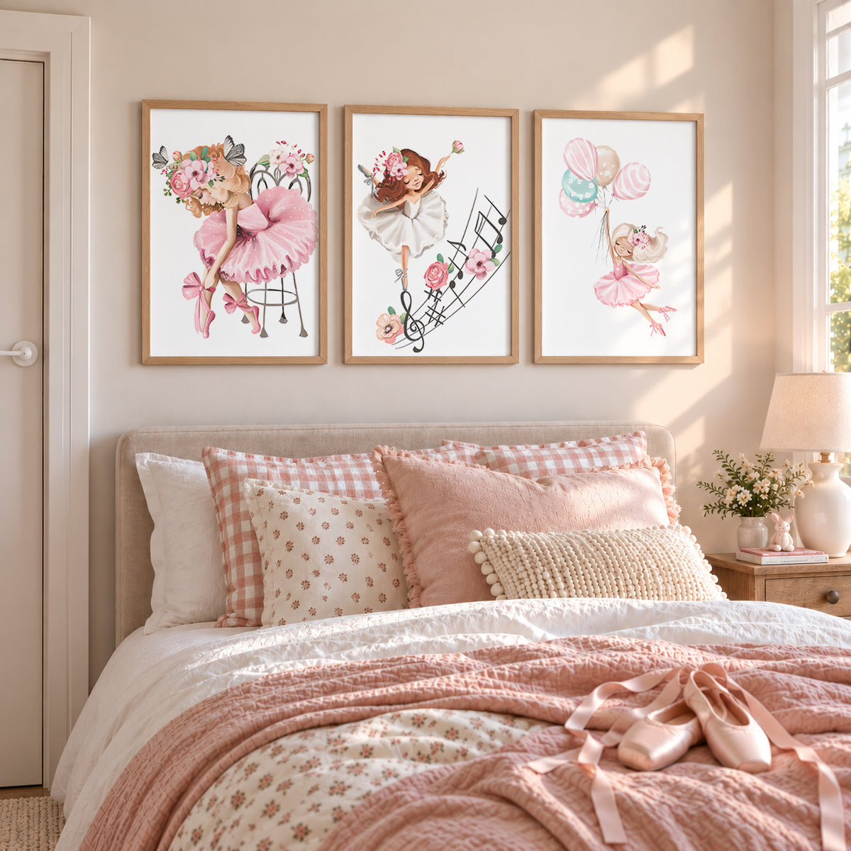 A set of three  oak framed wall art prints featuring illustrations of ballerinas, mounted on a wall above a bed in a child's bedroom.