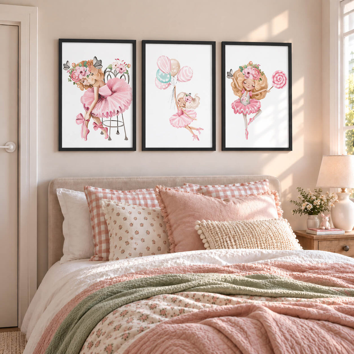 Three framed watercolor ballerina art prints in pink tones hang above a bed with pink and beige bedding in a softly lit bedroom.