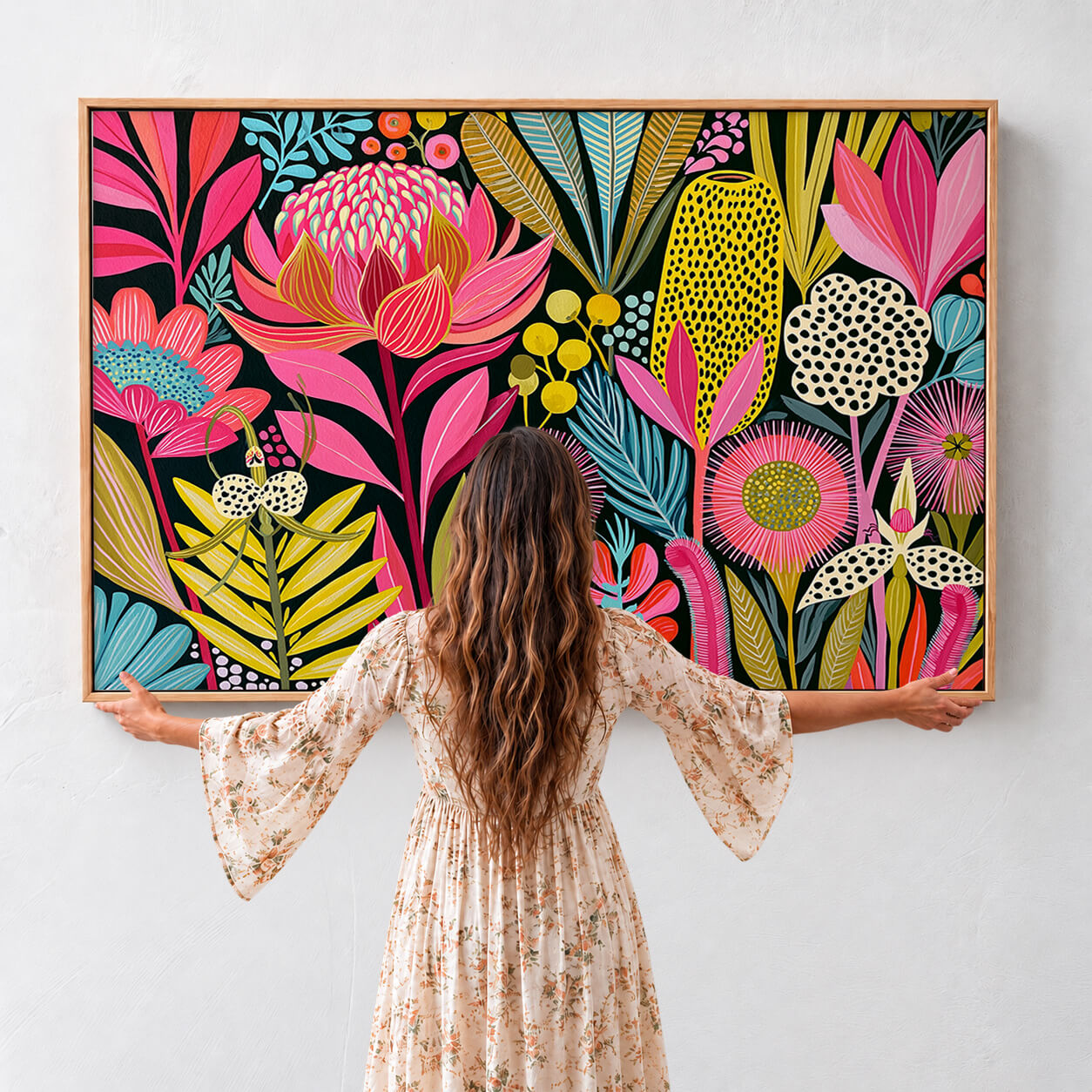 Large Australian native floral framed canvas featuring colourful waratahs, banksias and wildflowers shown with woman for scale